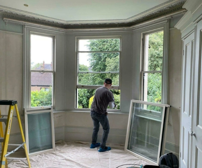 Expert RHS craftsman repairing a traditional wooden sash window in a historic Gibraltar Upper Town property.