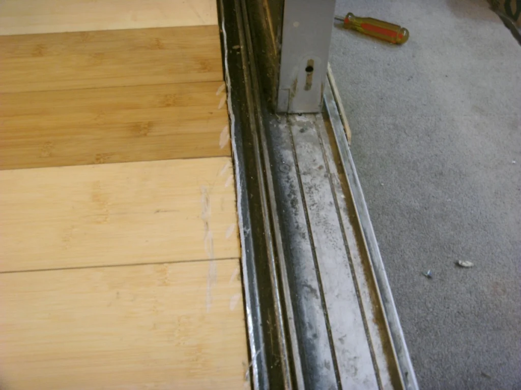 Professional sliding door repair in Ocean Village, Gibraltar, showing the replacement of salt-corroded rollers and track maintenance for a smooth glide.